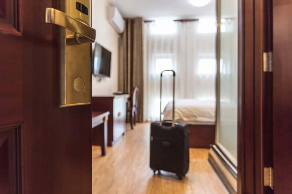 Hotel room door open with suitcase long distance caregiver self care