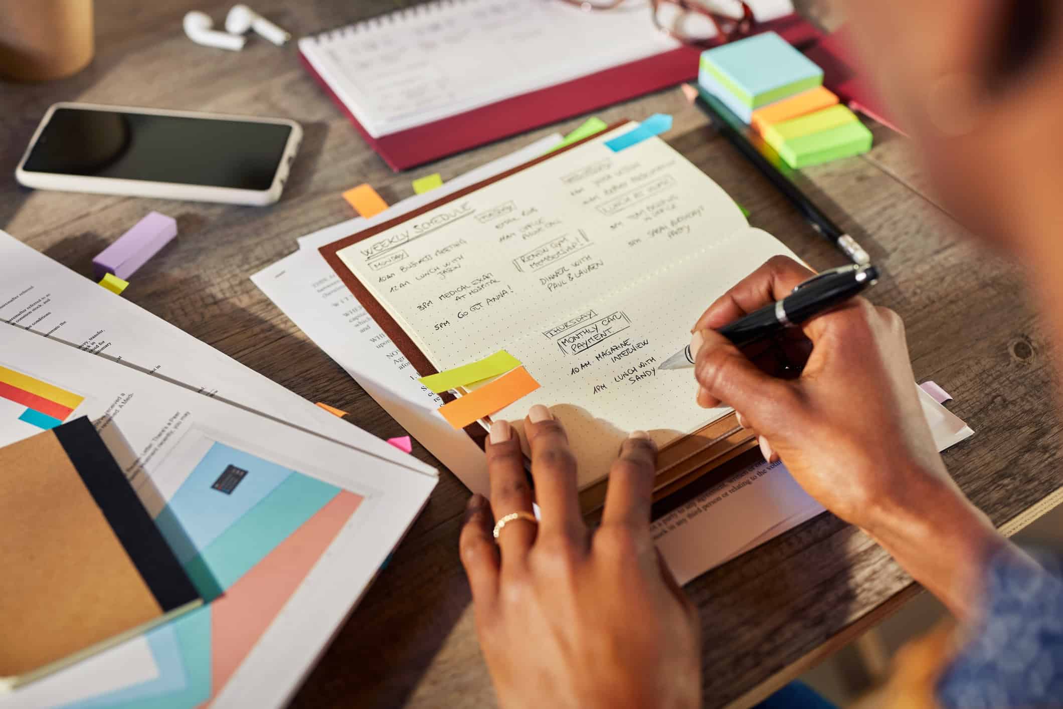 Woman writing notes by hand in a planner because she understand the importance of handwriting and memory