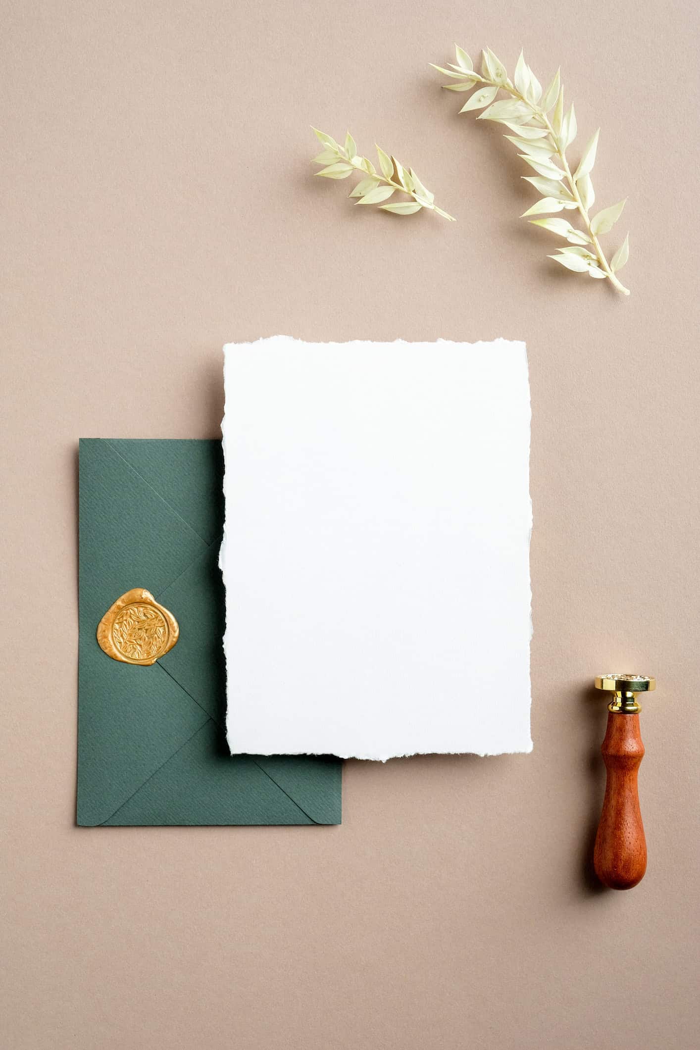 Personal stationery with green envelope, wax seal, blank note card, and wax stamp on a warm neutral background.