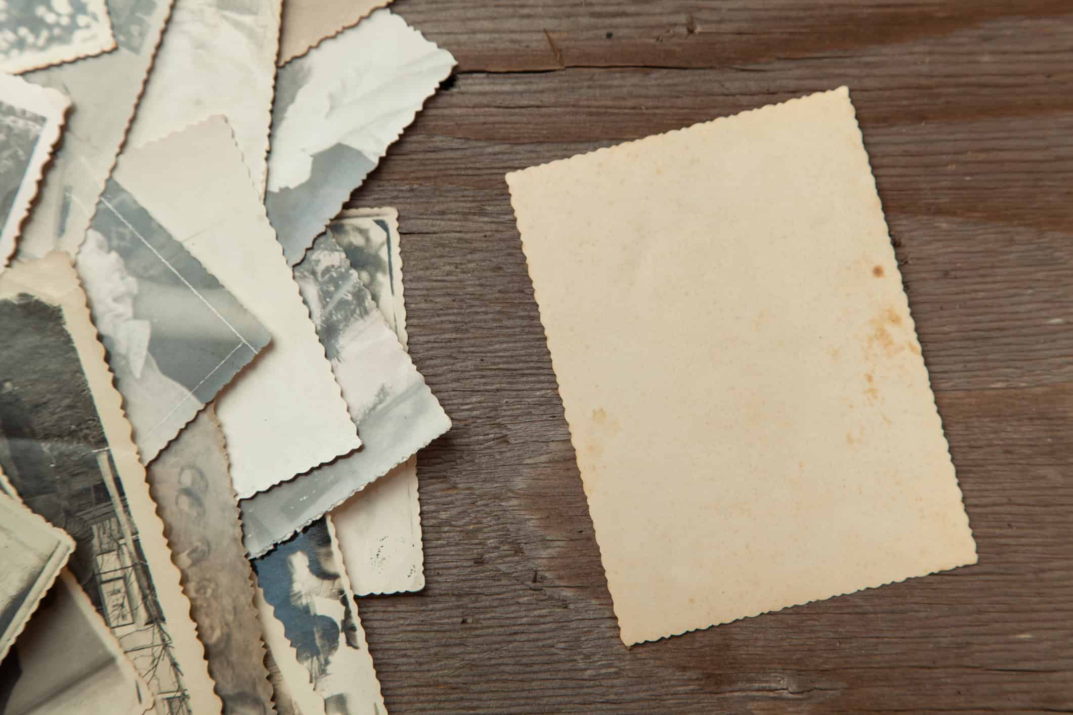 Old family photographs beside blank paper for writing down family stories.