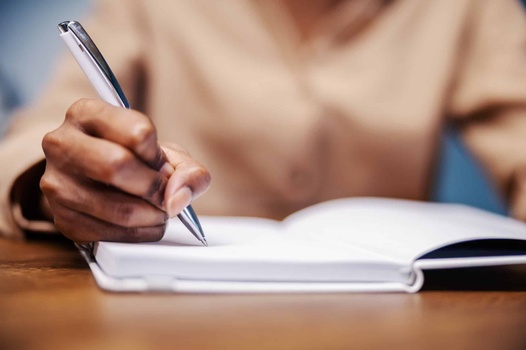 A woman writing care notes for a caregiving file in a notebook.
