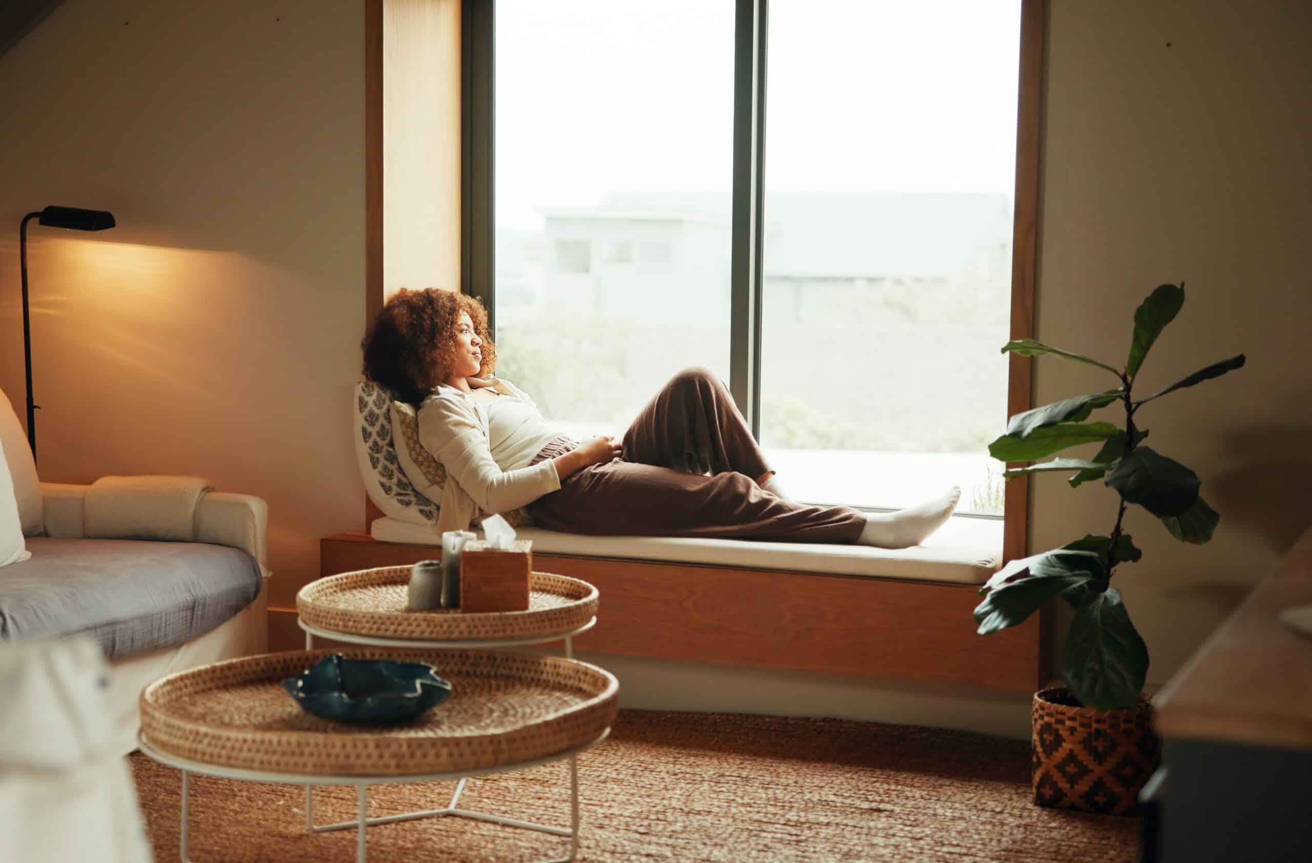 Woman enjoying the benefits of unstructured time by sitting in front of a sun lit window,