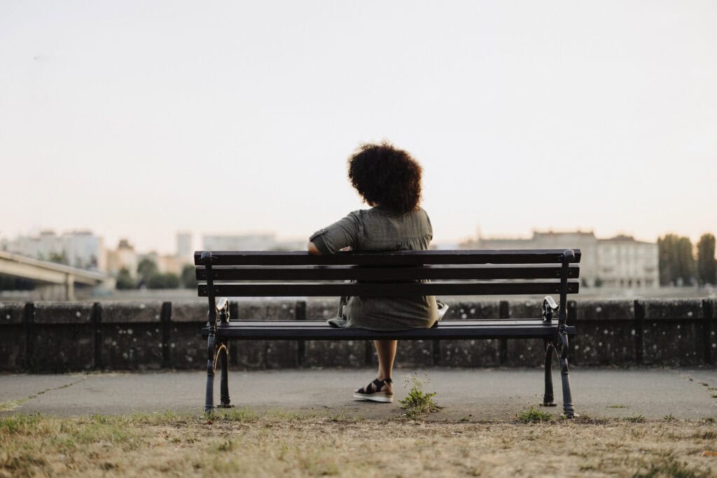 Woman sitting alone on a park bench taking a break from caregiving.