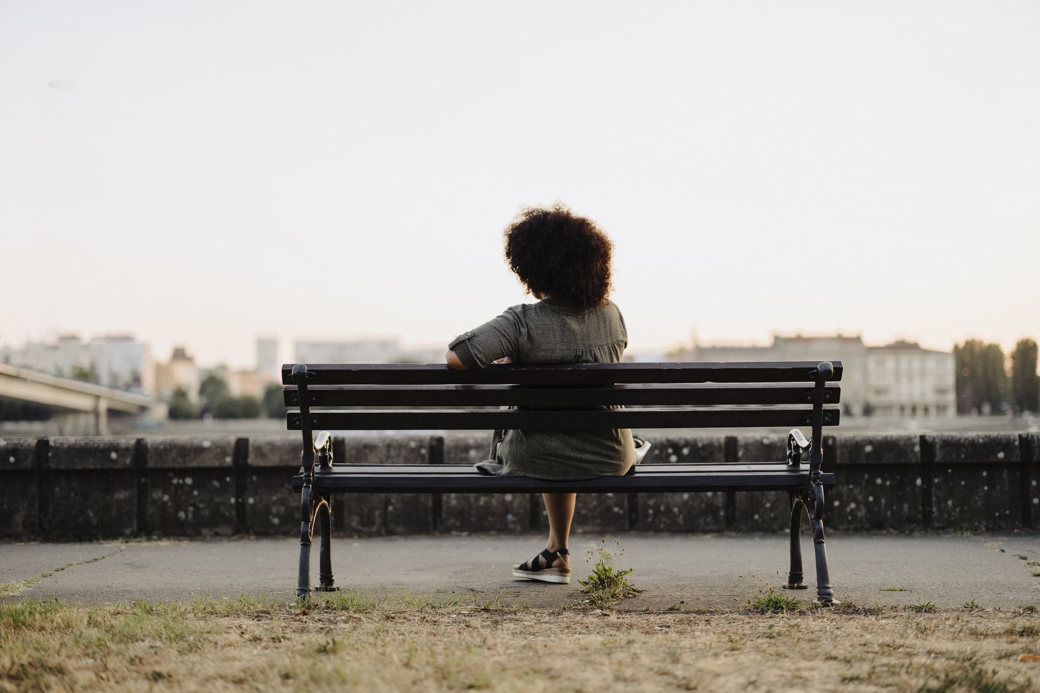 Woman sitting alone on a park bench taking a break from caregiving.